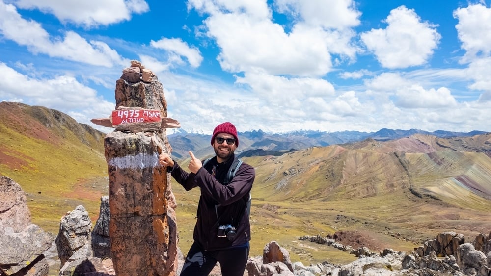 Young traveler pointing to the sign for high altitude at Machu Picchu